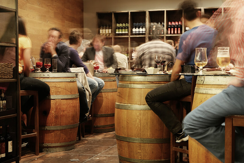 A busy bustling cask-themed bar with wooden barrel tables