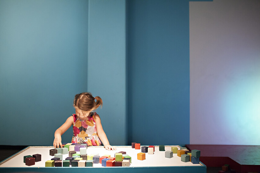 A little girl playing Lego in a kindergarten with blue walls