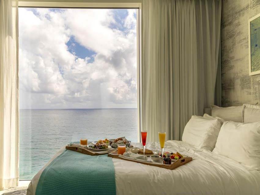 a hotel room design near the sea with the big a window and a bed for a couple