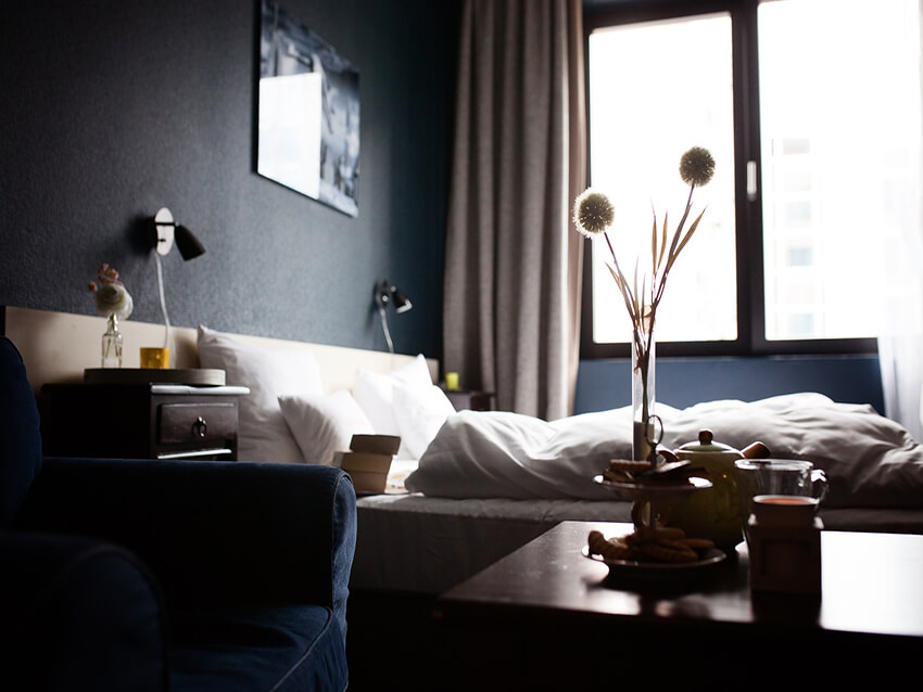a simple cozy hotel room with a dark blue sofa and a table