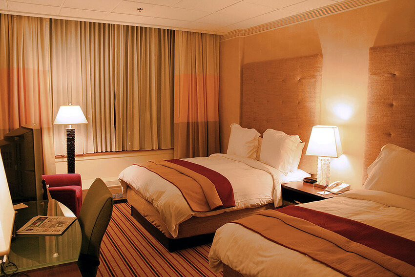 A four-bed hotel room with a work table and two beside lamps 